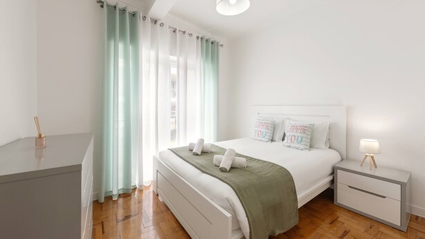 A modern bedroom with a bed, bedside tables, and a desk.