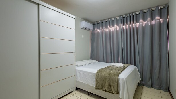 Ein Schlafzimmer mit einem Bett, einem Kleiderschrank, einer Klimaanlage und grauen Vorhängen.