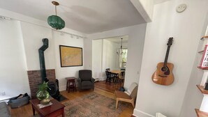 A living room with a fireplace, a dining area, and a guitar on the wall. - Cozy townhouse minutes from downtown Portland on a car free island (Portland)