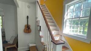 A staircase with wooden steps and white railings, a guitar leaning against the wall, and a window with a view of trees. - Cozy townhouse minutes from downtown Portland on a car free island (Portland)