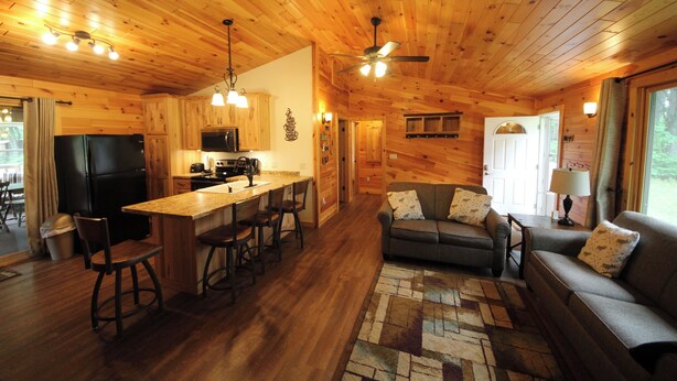 A wooden cabin interior with a kitchen, dining area, and living room. - White Potato Lake Cabin Retreat (Pound)