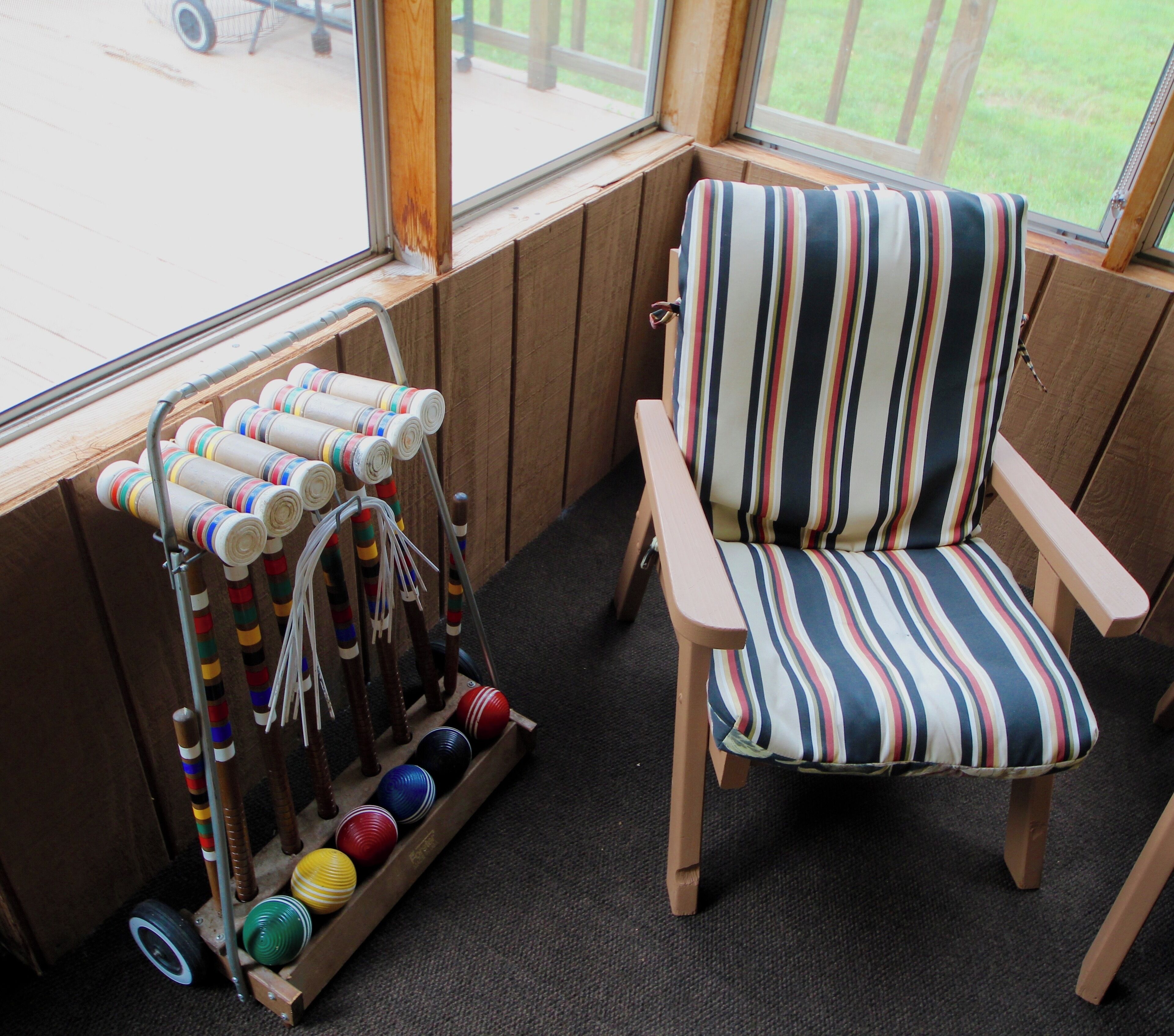 Una habitación con una silla a rayas, una ventana y un perchero con bolas de colores.