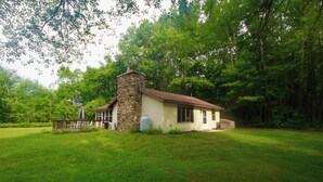 A small stone building with a wooden deck and a grassy yard. - White Potato Lake Cabin Retreat (Pound)