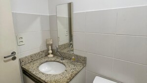 A small bathroom with a white sink, a mirror, and a toilet. - Luxury apartment in Maracanã (São Francisco Xavier Rio de Janeiro)