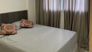 A hotel room with a bed, grey curtains, and patterned pillows. - Luxury apartment in Maracanã (São Francisco Xavier Rio de Janeiro)