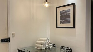 A dining area with a glass table, black chairs, a hanging light fixture, and a framed picture on the wall. - Luxury apartment in Maracanã (São Francisco Xavier Rio de Janeiro)
