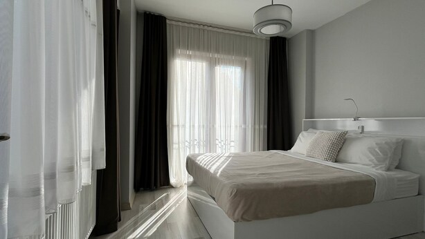 A modern bedroom with a large bed, a bedside table, and a hanging light fixture. - A-Chic 1-bedroom apartment with WiFi, AC in vibrant Istanbul (İstanbul)