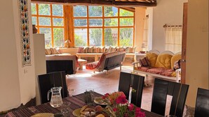 A dining area with a table set for two, a pitcher, glasses, and a bowl of corn on the cob. - Andean Cottage w/ Garden & Workspace near Urubamba (Urubamba)