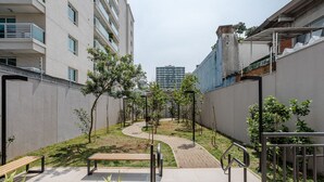 A pathway lined with trees and benches in a residential area with modern buildings. - Noas - Apartments in the South Zone of SP (São Paulo)