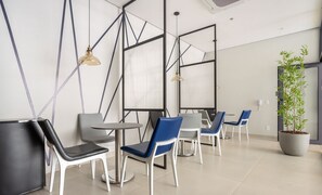 Een modern interieur met een zithoek bestaande uit witte en blauwe stoelen, een ronde tafel en hanglampen.