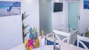 A modern kitchen with a marble countertop, a built-in sink, and a dining area with white chairs. - Raintree Suites (St. John)