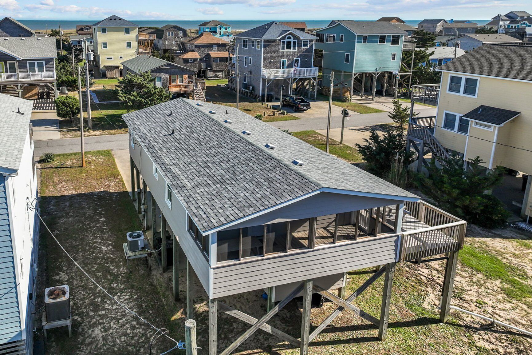 A coastal residential area with houses, including a two-story structure with a balcony and a small deck.