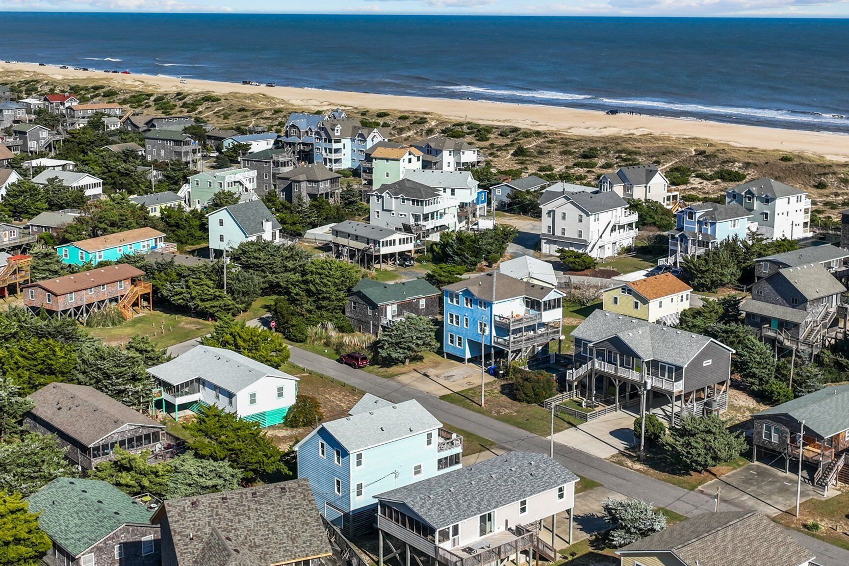 A coastal residential area with houses, some with balconies, and a beach in the background.