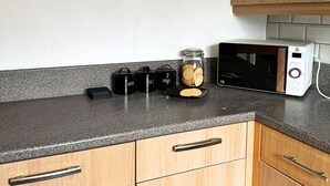 Une cuisine avec une affiche ancienne, un four à micro-ondes et des bocaux posés sur le plan de travail.