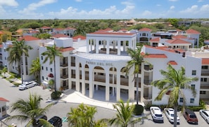 A multi-story hotel with a central courtyard, palm trees, and a clear sky.