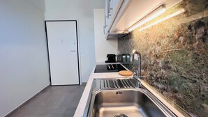 A modern kitchen with a stainless steel sink, a black toaster, and a marble backsplash. - Fifth Sense in Athens by ΜΡS (Athina)