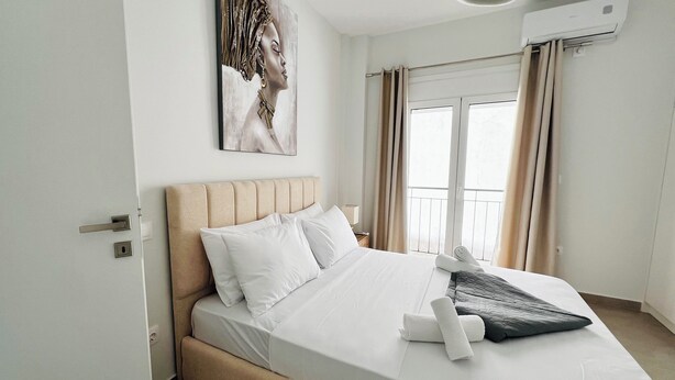 A hotel room with a bed, a painting on the wall, and a window with curtains. - Fifth Sense in Athens by ΜΡS (Athina)