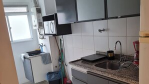 Eine moderne Küche mit dunklen Schränken, einer Spüle aus Edelstahl und einem Fenster, das für natürliches Licht sorgt.