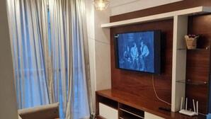 Ein modernes Wohnzimmer mit einem Flachbildfernseher an einer Holz-Unterhaltungseinheit, einem Sofa und einem gemusterten Teppich.