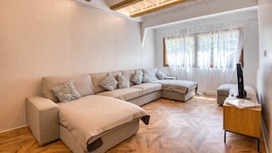 Una sala de estar moderna con un sofá modular, piso de madera, un ventilador de techo y un escritorio con una computadora.