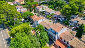 Zona residencial costera con casas de tejas de terracota, abundante vegetación y una vista despejada del mar.