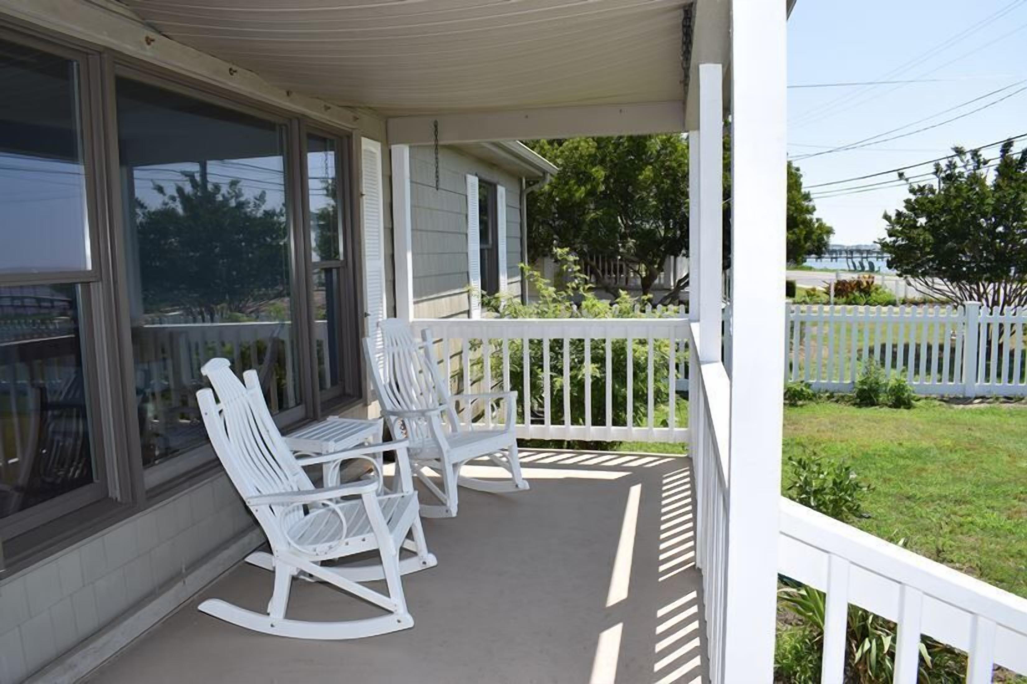 A porch with two rocking chairs and a white picket fence.