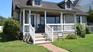 A two-story house with a covered porch, a front door, and a small front yard.