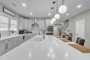 A modern kitchen with white cabinetry, a central island, stainless steel appliances, and pendant lighting.