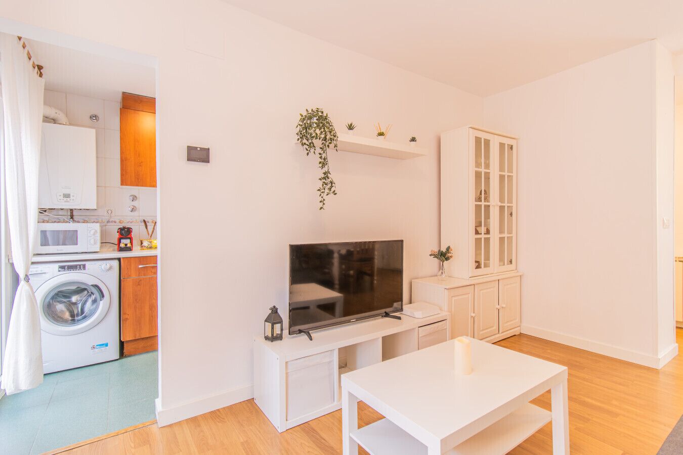 A compact living space with a washing machine, microwave, and a small kitchen area.