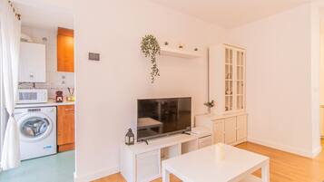 A compact living space with a washing machine, microwave, and a small kitchen area.