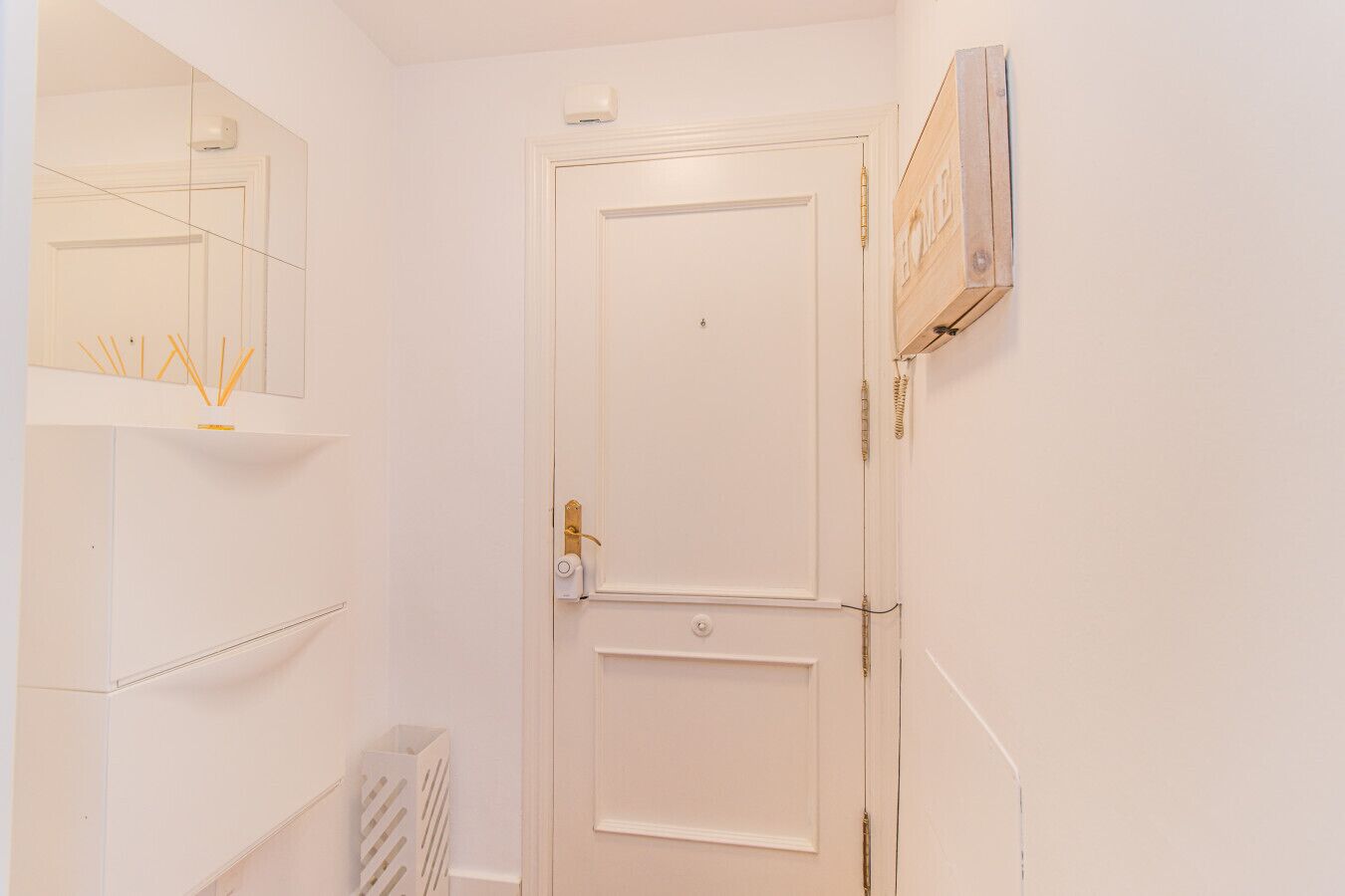 Una porta bianca con una piccola finestra, un termosifone sottostante e un lampadario a parete.