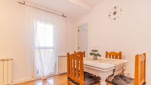A dining area with a table, chairs, a clock, and a radiator. - Pyrenees Escape  with Terrace & BBQ (Sabiñánigo)