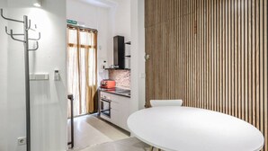 A modern kitchen with a brick backsplash, a white table, and a wooden slat wall.