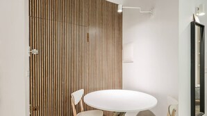 A room with a wooden slat wall, a round white table with two chairs, and a mirror on the wall.