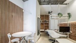 A modern interior with a white table and chairs, a brick wall, and a white shelving unit with plants.
