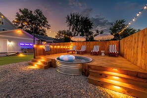 An outdoor hot tub area with wooden decking, lounge chairs, and string lights. - Private Cinema + Cowboy Pool, Putt Putt, Arcade (Indianapolis)