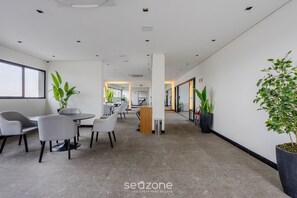 A modern office space with a reception desk, seating area, and potted plants.