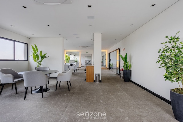 A modern office space with a reception desk, seating area, and potted plants. - VNU - Apartamentos próximos de atrações em SP (São Paulo)
