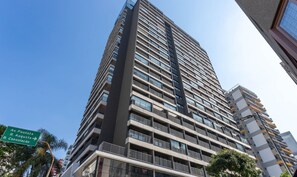 A tall, modern high-rise building with multiple balconies and large windows.