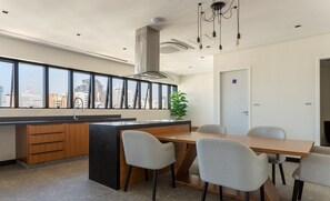 A modern kitchen with a large window, a central island, and a dining area with chairs.