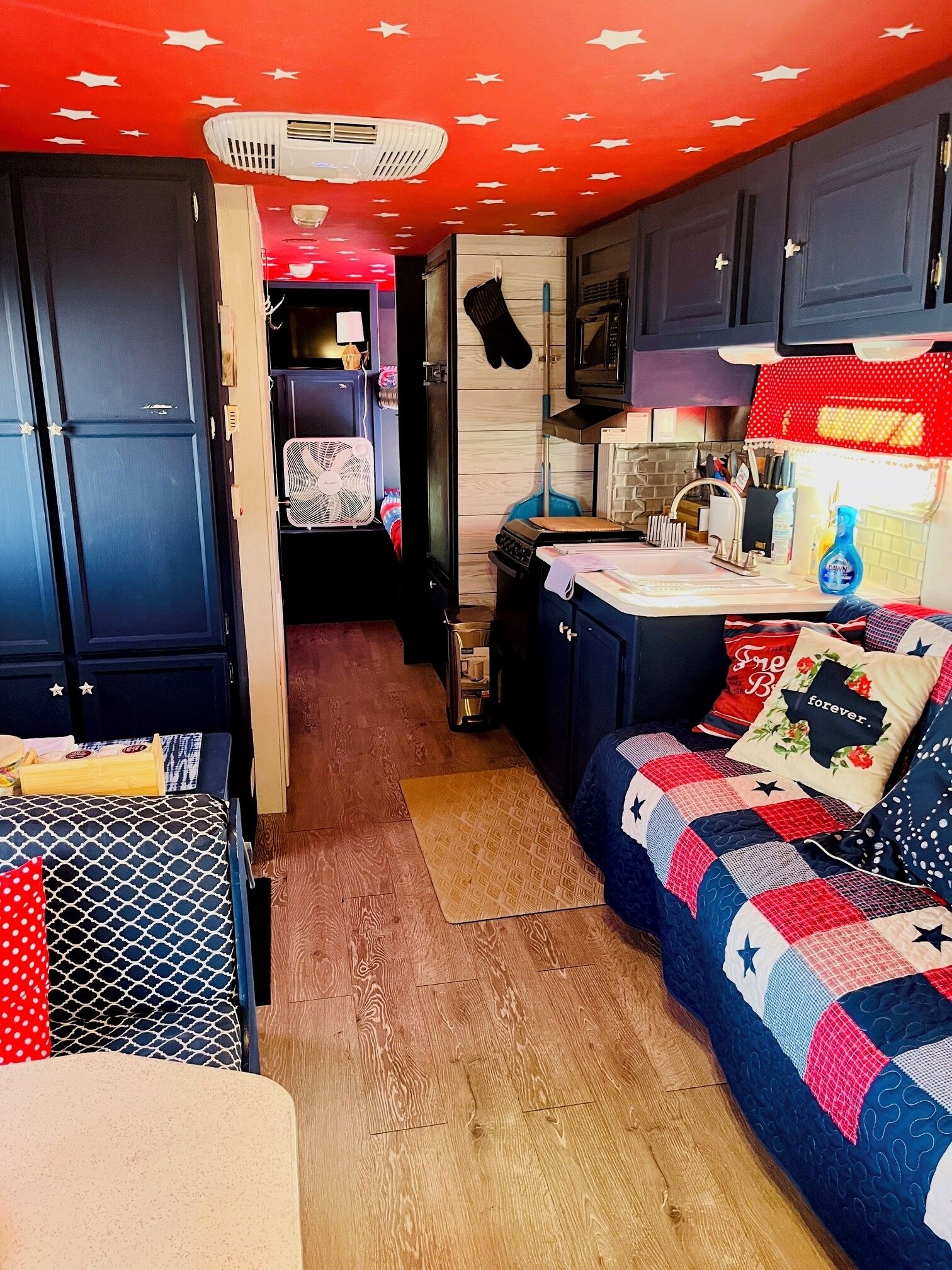 Een compact interieur van een camper met een kitchenette, een eethoek en een slaapgedeelte.