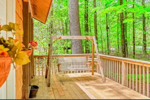 A wooden deck with a bench and a swing, surrounded by a wooden railing, set in a forested area. - Rustic Glam, 3-bedroom home in Lovely Blakeslee with Games, AC, Firepit & Beach (Blakeslee)