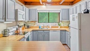 Una cucina moderna con pensili grigi, un piano di lavoro in legno, forno integrato e un'ampia finestra.