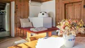 A wooden cabin interior with a bed, a table with a vase of flowers, and a wooden bench. - Ferienhaus S' Tobiasa (Schönwies)