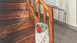 A wooden staircase with a metal handrail and a white bag with floral embroidery hanging on the railing. - Ferienhaus S' Tobiasa (Schönwies)