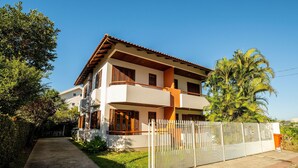 A two-story house with a balcony, a fenced yard, and a clear sky. - Beautiful Apartments Close to the Beach Stacy (Florianópolis)