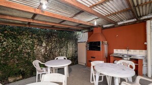 An outdoor patio with a barbecue grill, two round tables, and four chairs. - Beautiful Apartments Close to the Beach Stacy (Florianópolis)