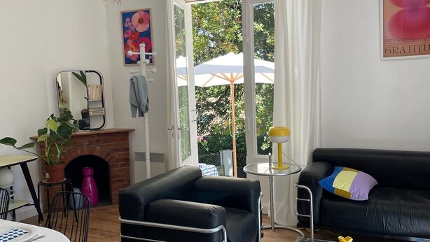 A modern living room with a fireplace, black leather sofa, and a dining area with a table and chairs. - House between Landes and Basque Country, Beach 3km away (Ondres)