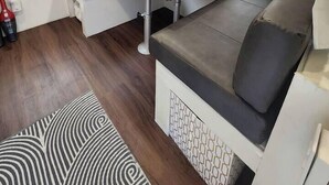 Un espace de vie compact comprenant un canapé, une petite table et un luminaire au plafond.