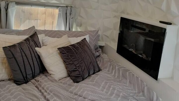 Une chambre à coucher avec un lit, des oreillers, une télévision et une cheminée.